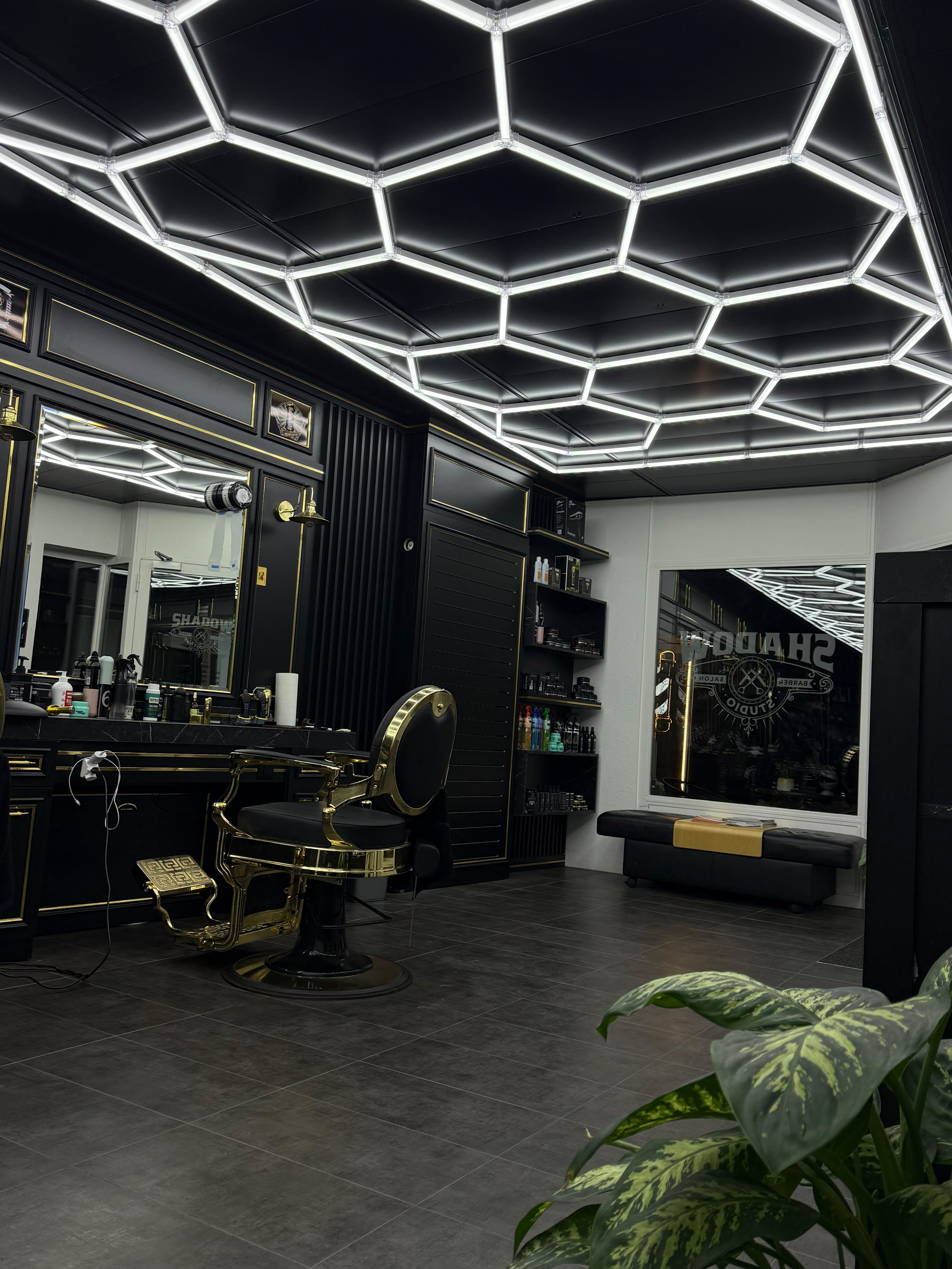 Innenraum des Shadow Studio mit goldenem Barberstuhl und Spiegelstation