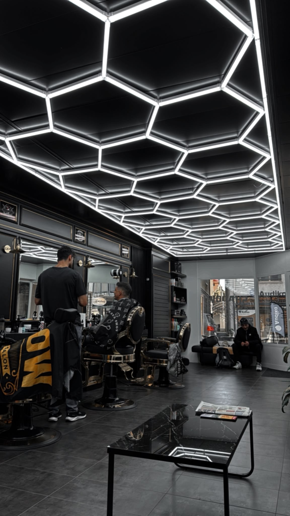 Barber bei der Arbeit unter der Wabenlicht-Decke im Shadow Studio